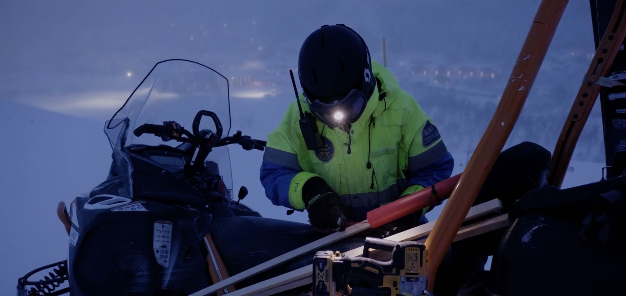 Arbetare med pannlampa och komradio vid skotern i skymningen