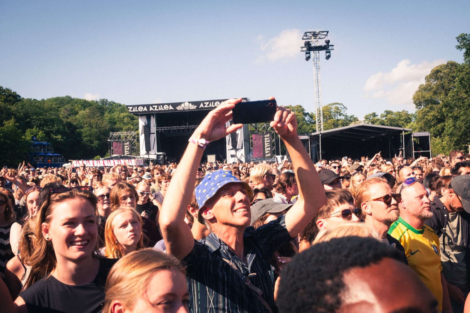 Publik i solen som filmar scenen med mobilen